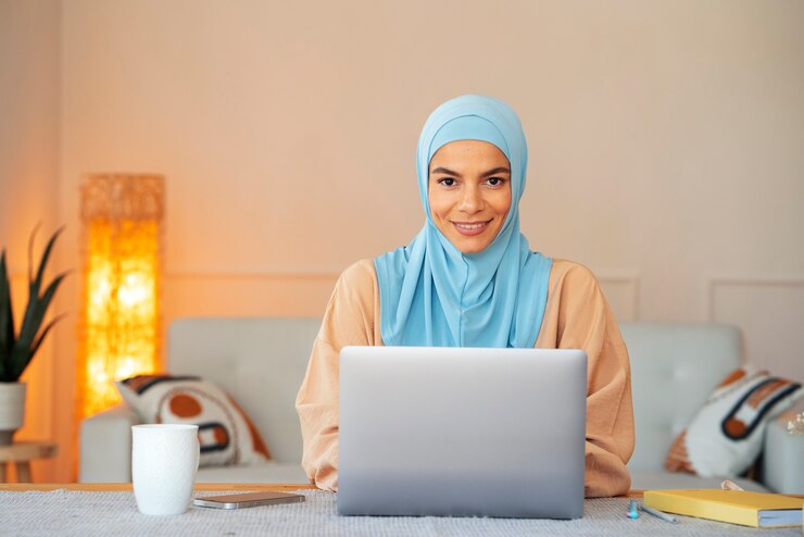 Woman in a hijab at a laptop, Online Quran Learning in the UK. Perfect for showcasing Learn Quran online UK courses, including Tajweed classes and Quran classes for kids,