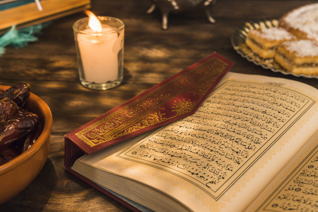 An open Quran with elegant Arabic script rests on a wooden table, creating a warm and spiritual Ramadan ambiance.