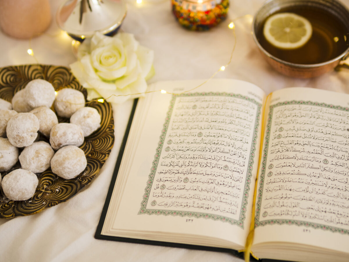 An open Quran with intricate Arabic calligraphy is placed on a white cloth,creating a serene and spiritual Ramadan atmosphere.